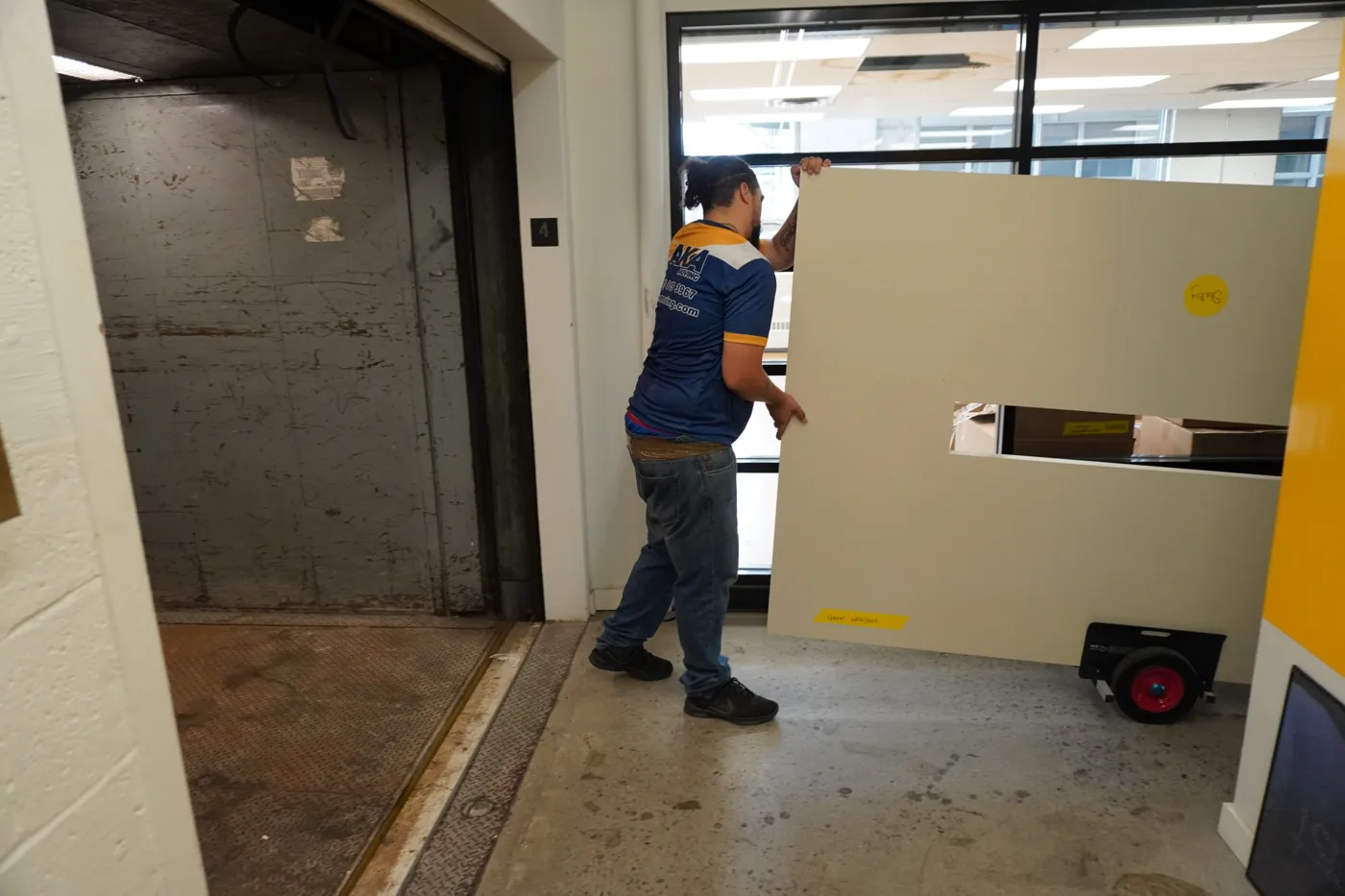Déménageur AKA entrant une section de table dans le monte-charge lors d’une relocalisation de bureau à Montréal